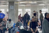 People sit and look at the camera as they wait inside a hospital in Gaza