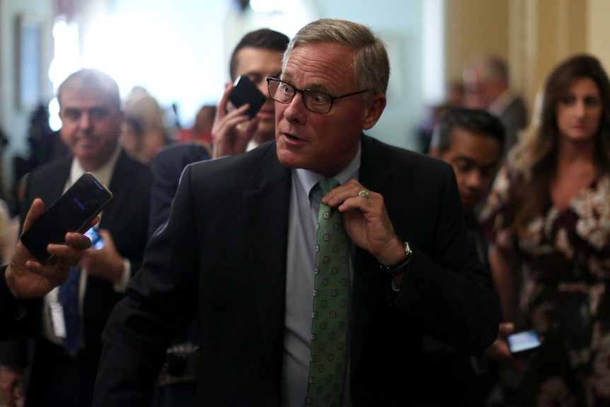 Richard Burr answering a question while surrounded by media