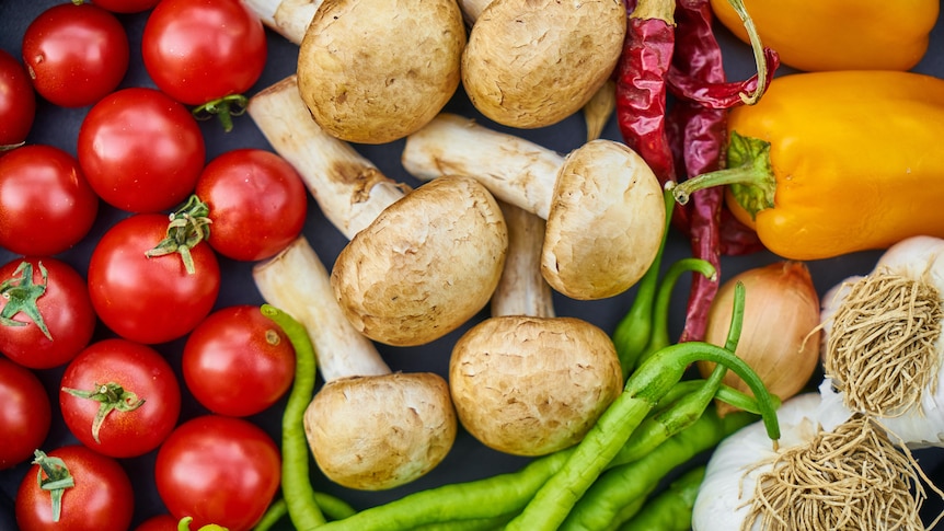 An overview of some vegetables including cherry tomatoes, button mushrooms, green  beans and yellow capsicum