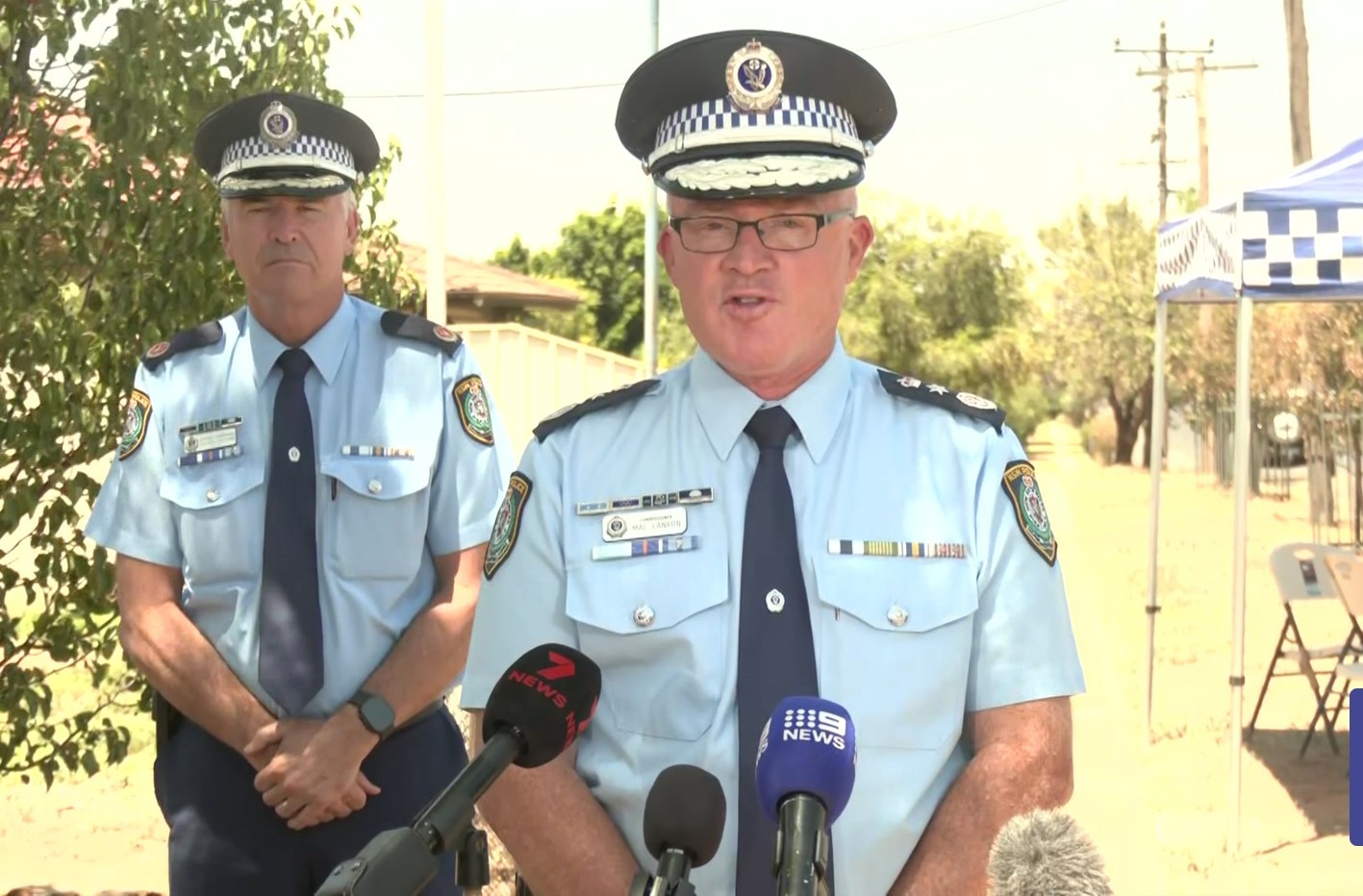 Dois policiais de NSW estão em frente a um conjunto de microfones.