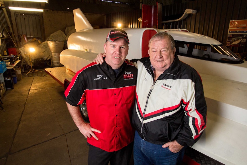 Ken and David Warby stand next to their boat.