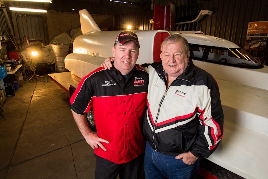 Ken and David Warby stand next to their boat.