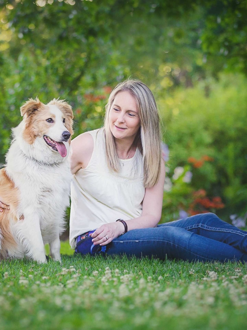 Woman sits with large dog on grass