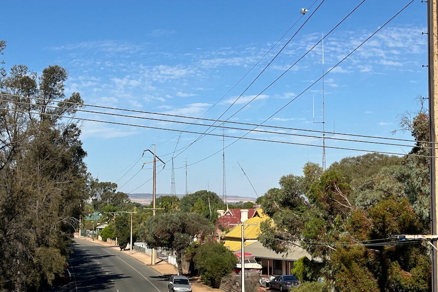 Many houses, cars and TV towers when looking over a street from a bridge. 