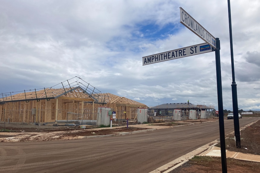 A house under construction, behind a street sign. 