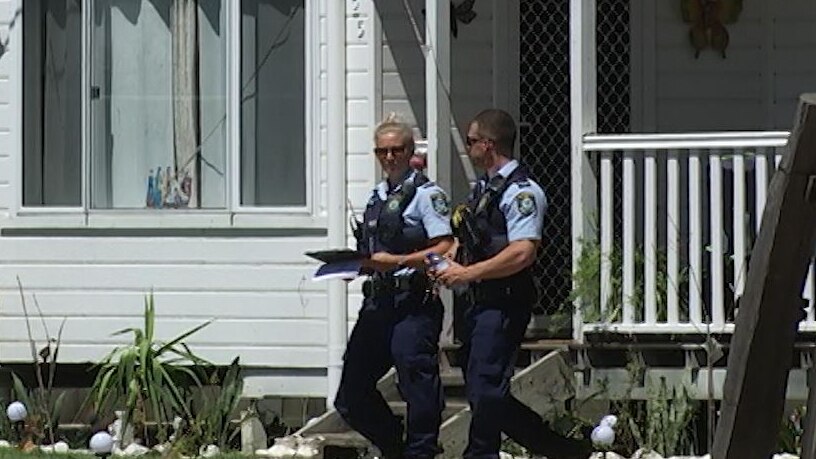 A male and female police officer in uniform walking by a home
