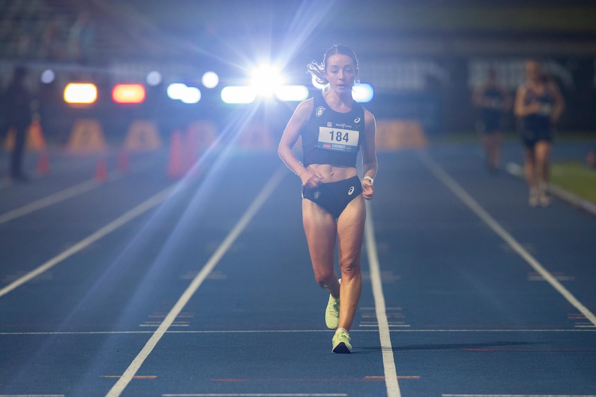 Australian race walker Jemima Montag competes on the race track at night.