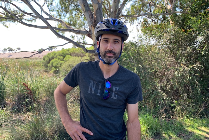 A man wearing a bike helmet and looking at the camera.
