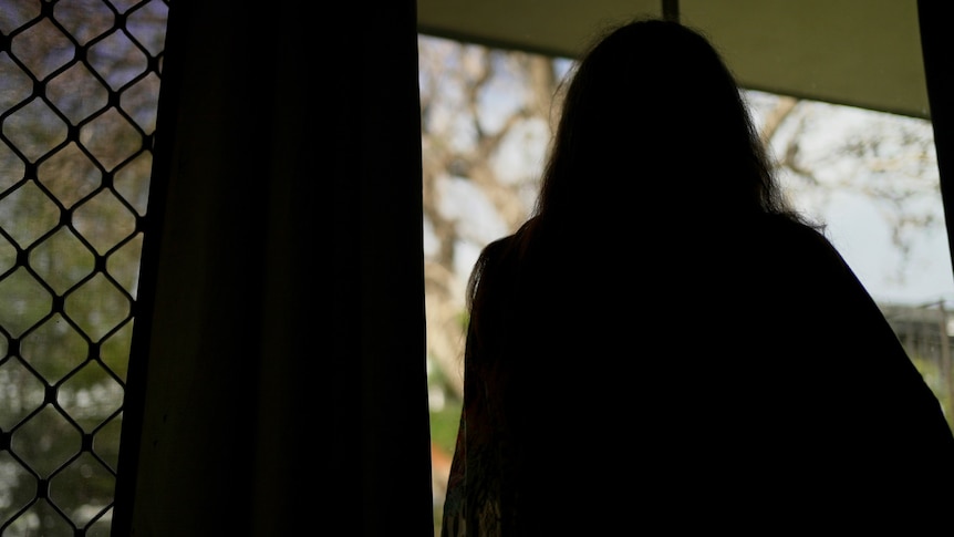 Jane has overcome heroin dependence, silhouette standing by a window