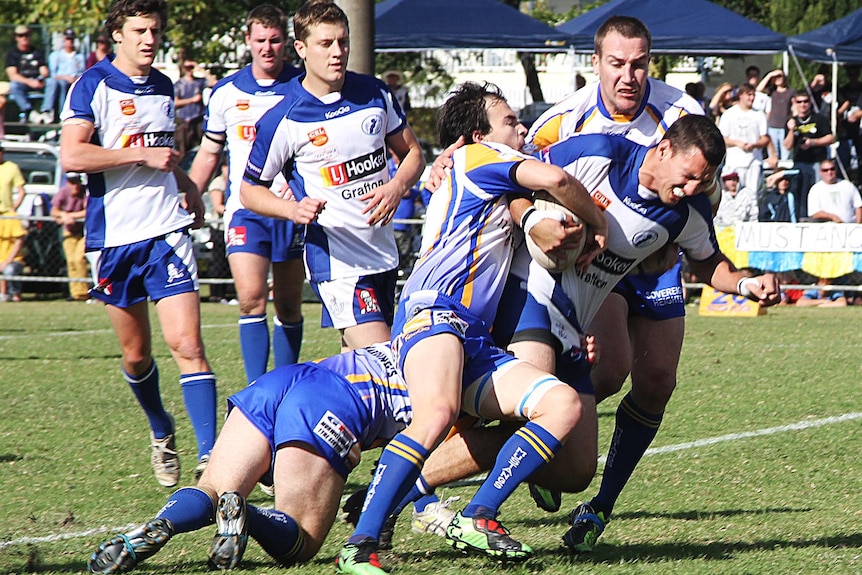 Murwillumbah Mustangs players tackle a Grafton Ghosts player during NRRRL grand final.