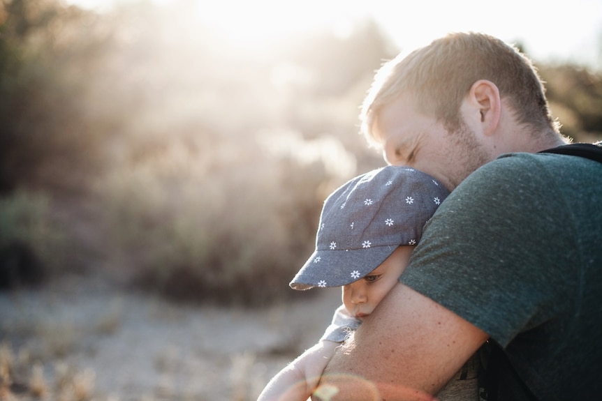 A man hugs a baby.