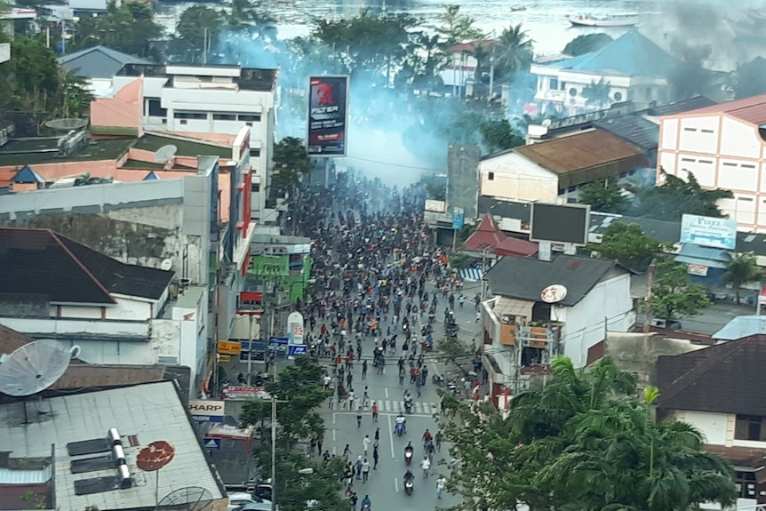 A crowd of protesters clash with authorities on the street, seen from a distance