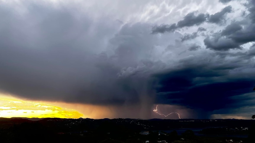 Storm cells range with lightning thundering before a golden sunset glow