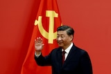 在共产党党旗前的习近平在挥手。