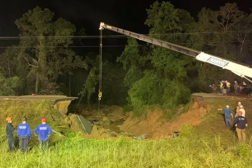 A crane is used to remove debris from a hole in a US highway.