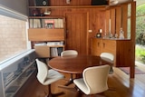 Wood panelled lounge with round table and swivel chair dining suite  