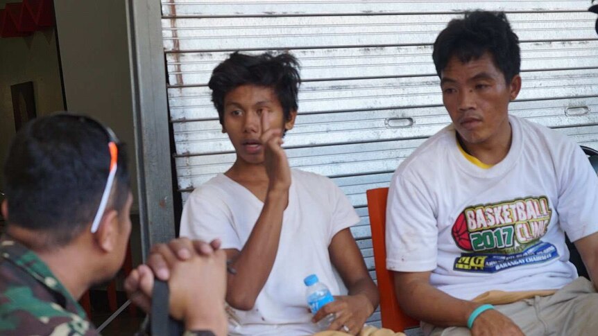 Three Christians wearing white shirts talk after fleeing Islamic State fighters in Marawi.