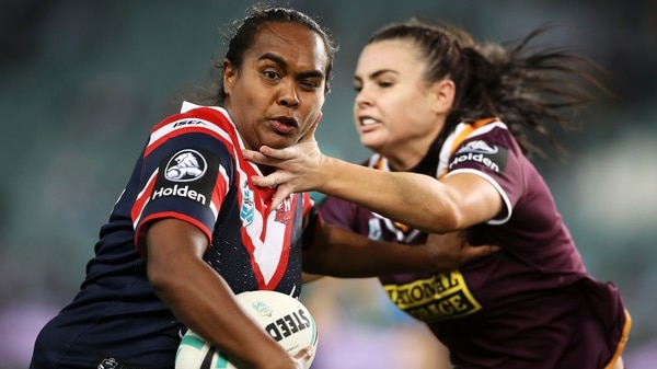A woman attempting to tackle another woman with a ball