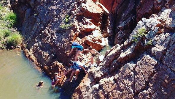 People swimming in a rock-lined waterhole