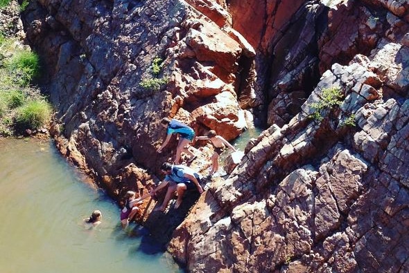 People swimming in a rock-lined waterhole