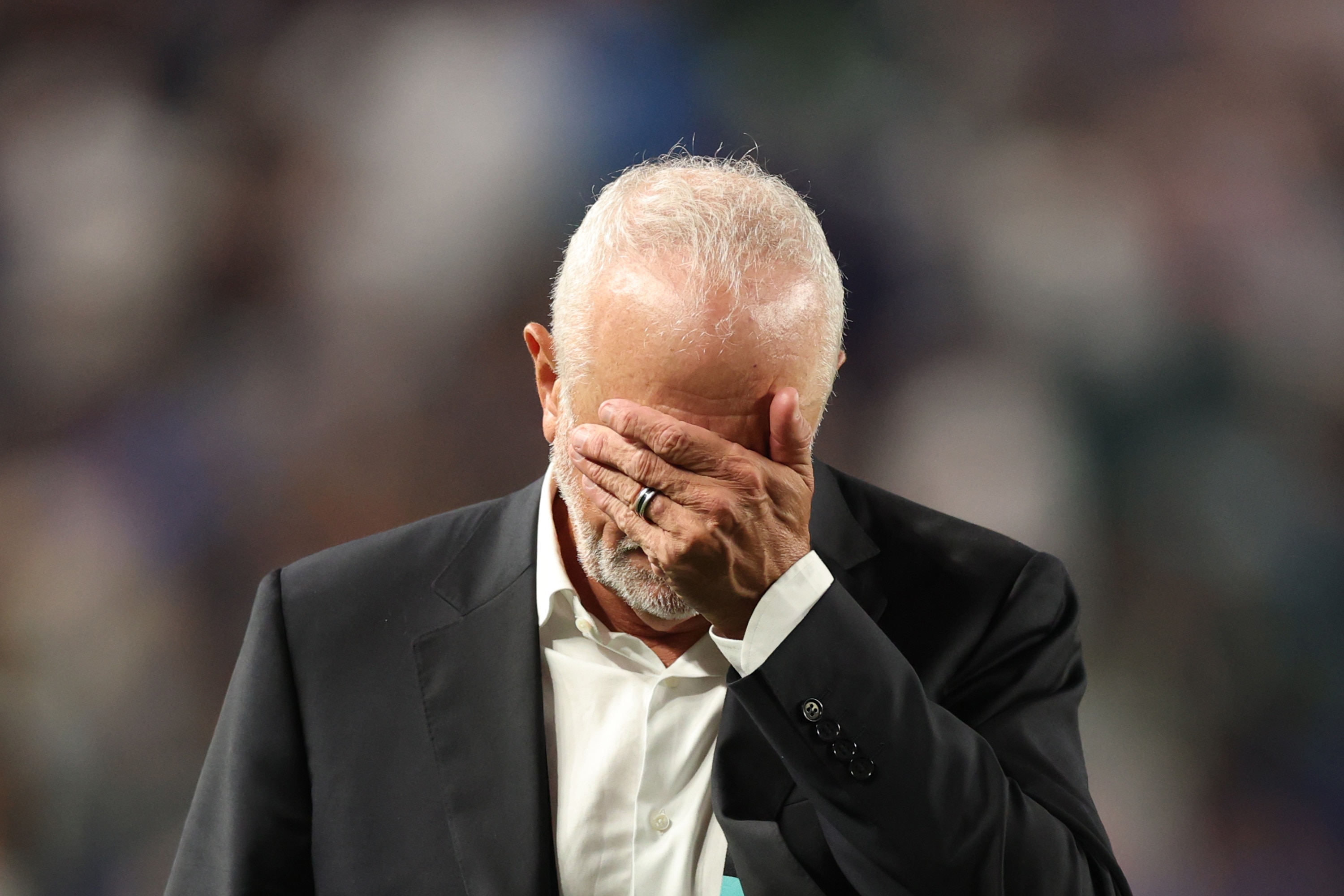Graham Arnold has his hand over his eyes and head bowed.