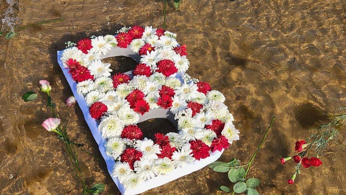 The letter B made out of flowers floating in the water.