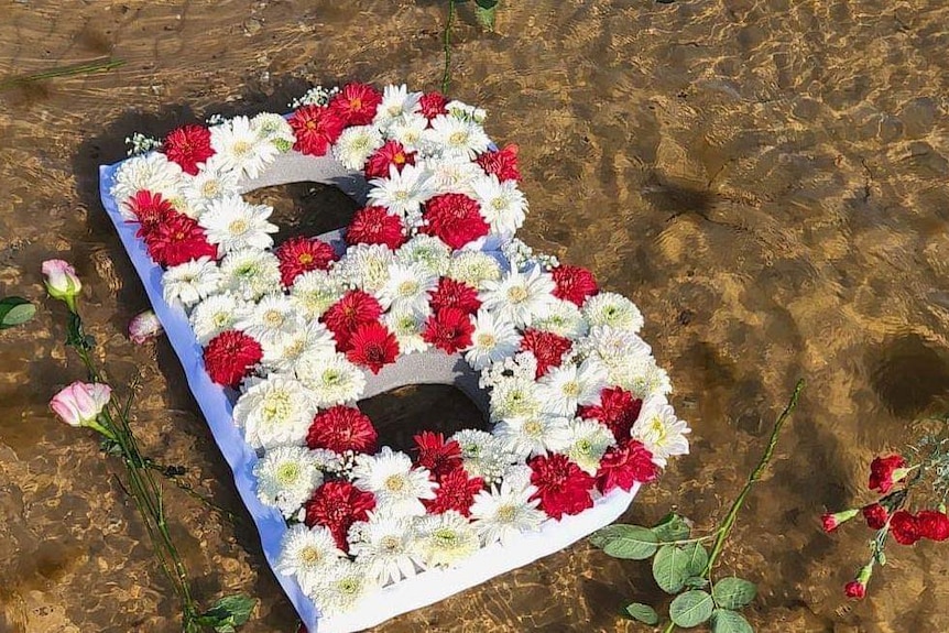 The letter B made out of flowers floating in the water.