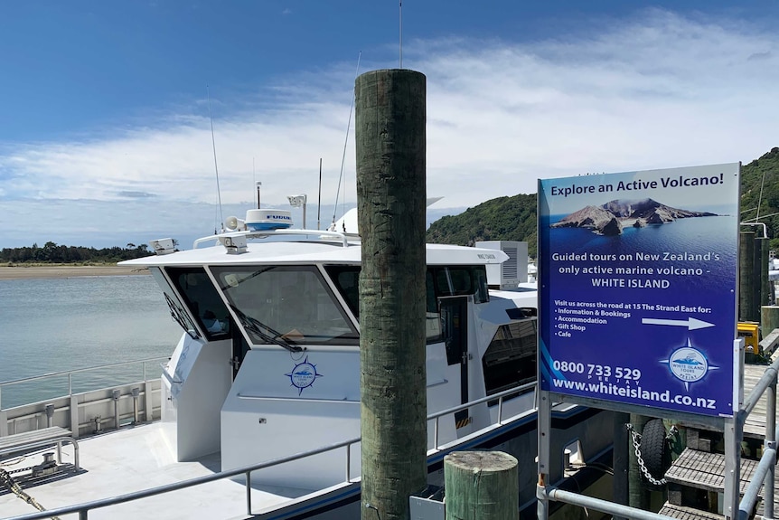 A boat docked in the water next to a sign reading 'explore an active volcano!'