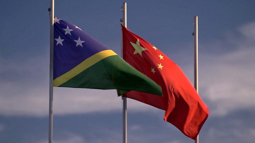 Two flags on flagpoles, one is for the Solomon Islands, the other is China's.