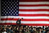 Donald Trump stands in front of a giant US flag, addresses US troops at a naval base.