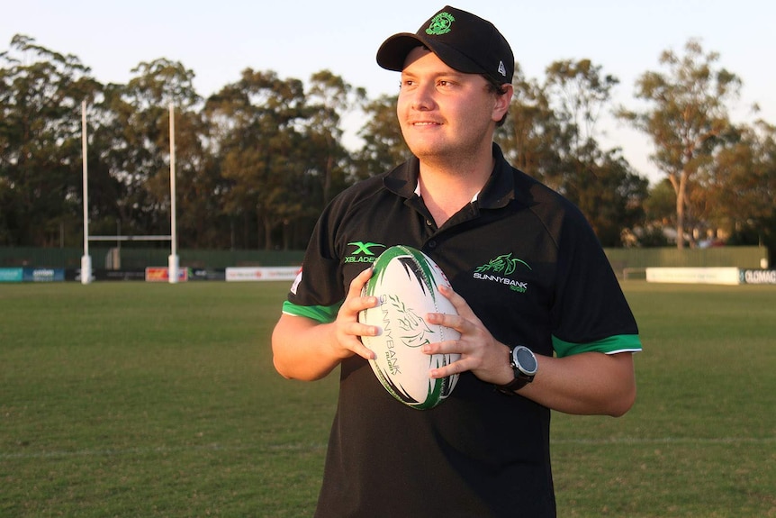 A man standing on a rugby union oval holding a football