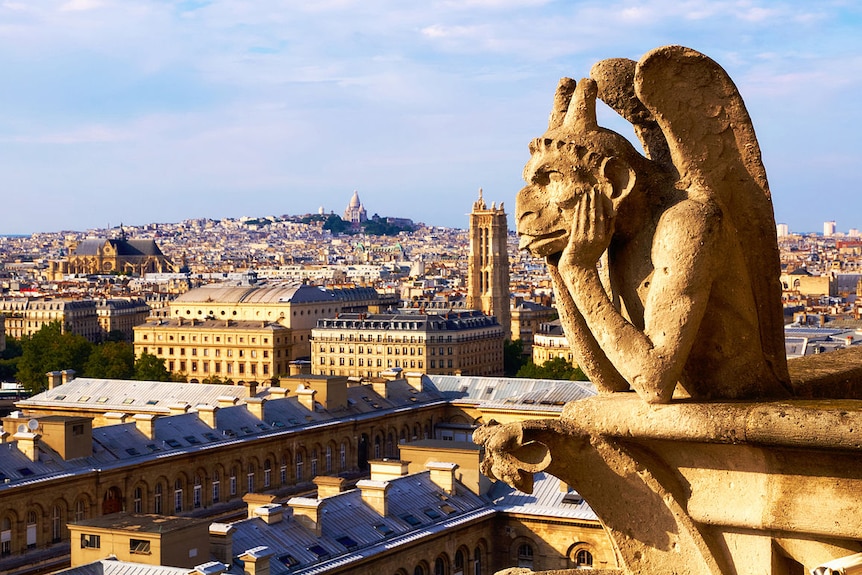 A warm photograph shows a despondent gargoyle looking over Paris in afternoon light.