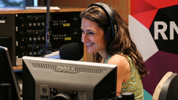 Patricia Karvelas smiles while sitting at her desk in front of a microphone