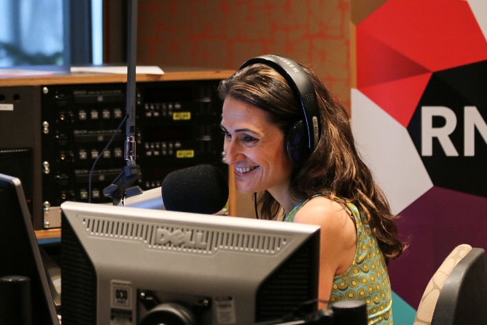 Patricia Karvelas smiles while sitting at her desk in front of a microphone