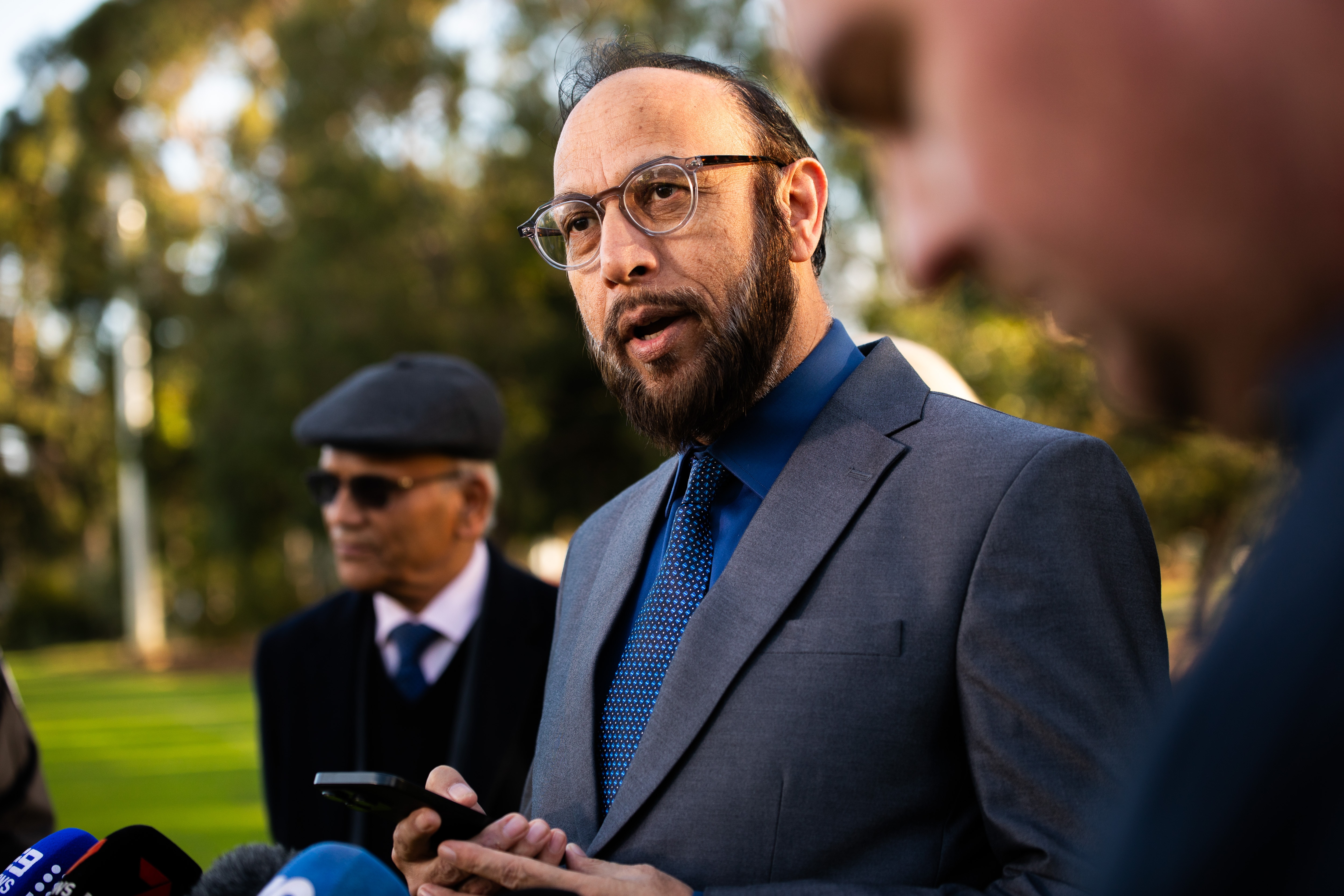 Abdullah Khan speaking in front of microphones.