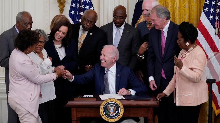 President Joe Biden hands a pen to Rep. Barbara Lee.