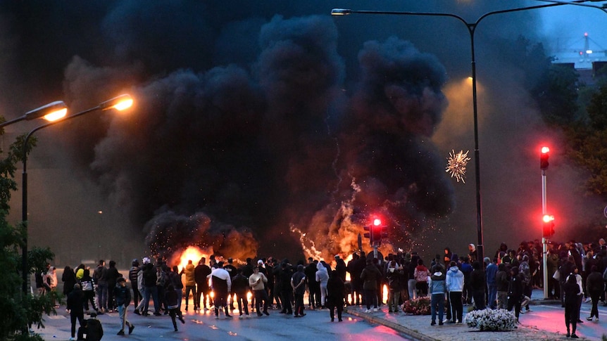 Riot police on the scene as smoke billows from burning tires and fireworks, as a few hundred protesters riot in the street.