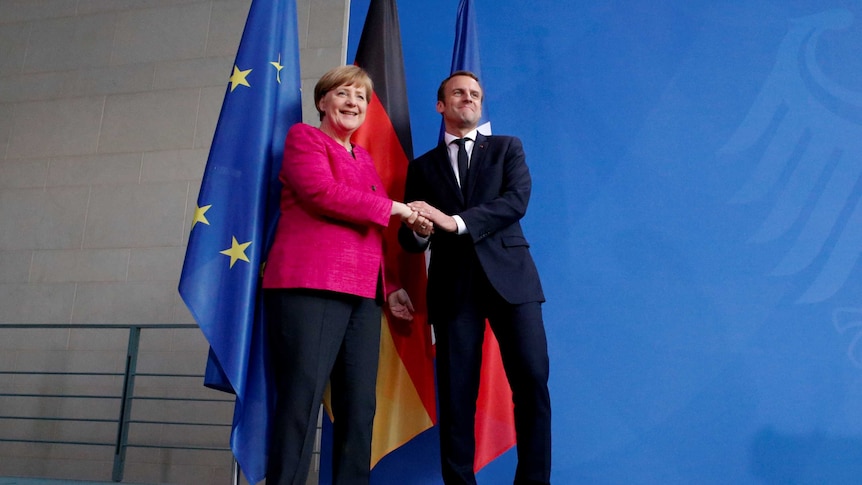 German Chancellor Angela Merkel and French President Emmanuel Macron shake hands.