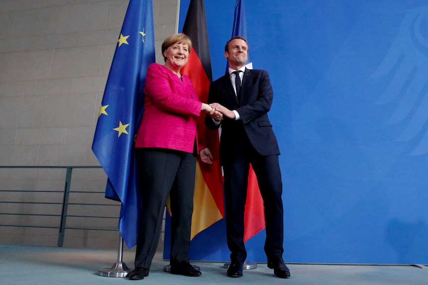 German Chancellor Angela Merkel and French President Emmanuel Macron shake hands.