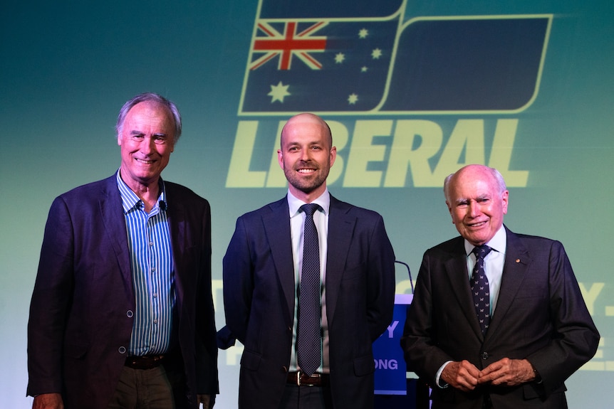 John Alexander, candidato liberal por Bennelong, Simon Kennedy y el ex primer ministro John Howard posan para una fotografía