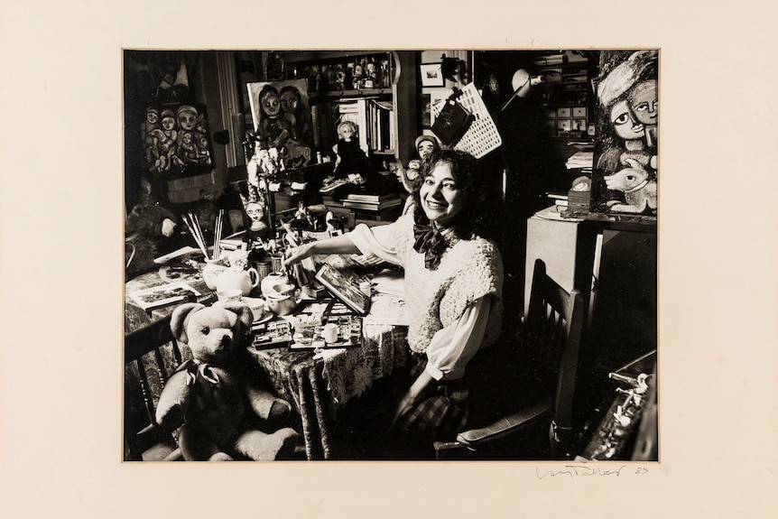 A black and white photograph of the artist Mirka Mora in her busy artists studio in 1986