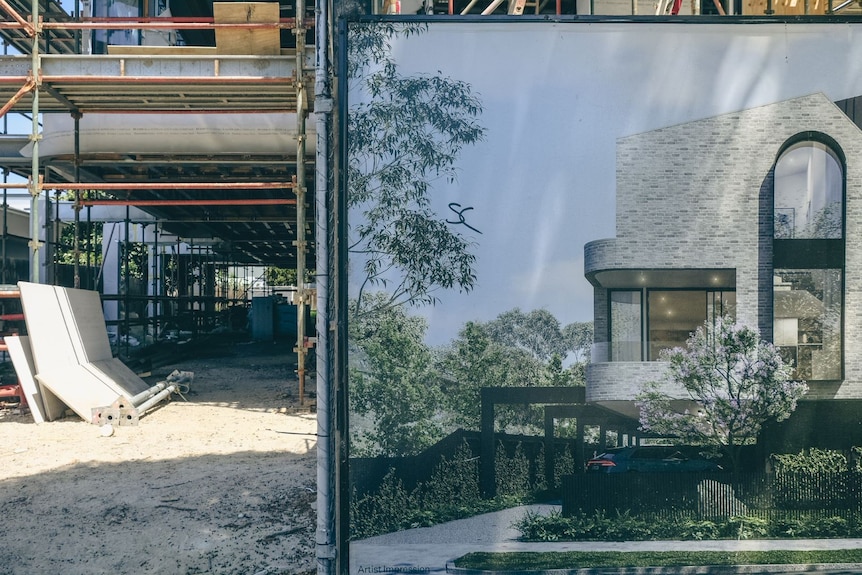 A sign with a picture of a white apartment building stands in front of a construction site