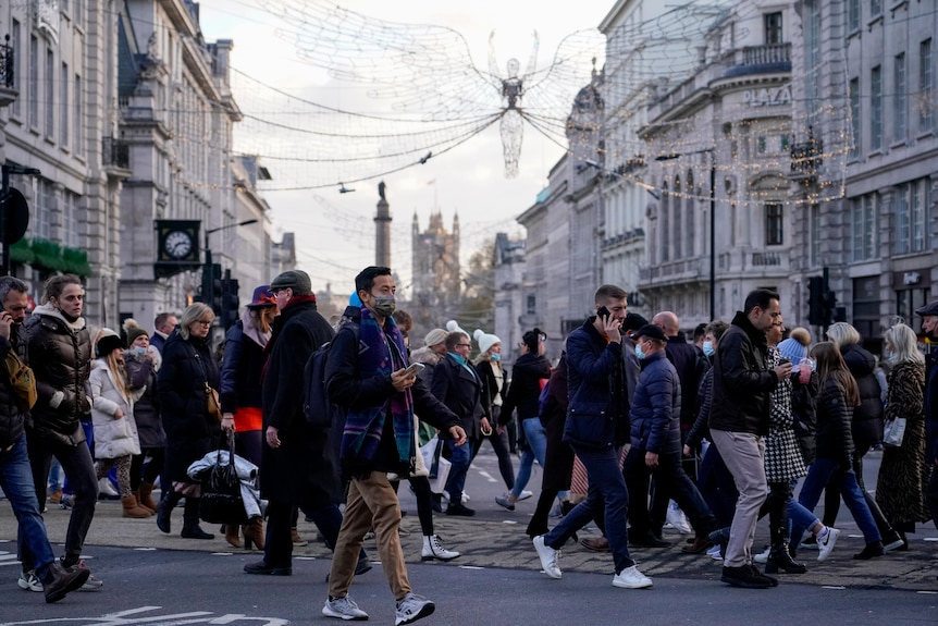 Pedestrians wear face masks while crossing the road in London