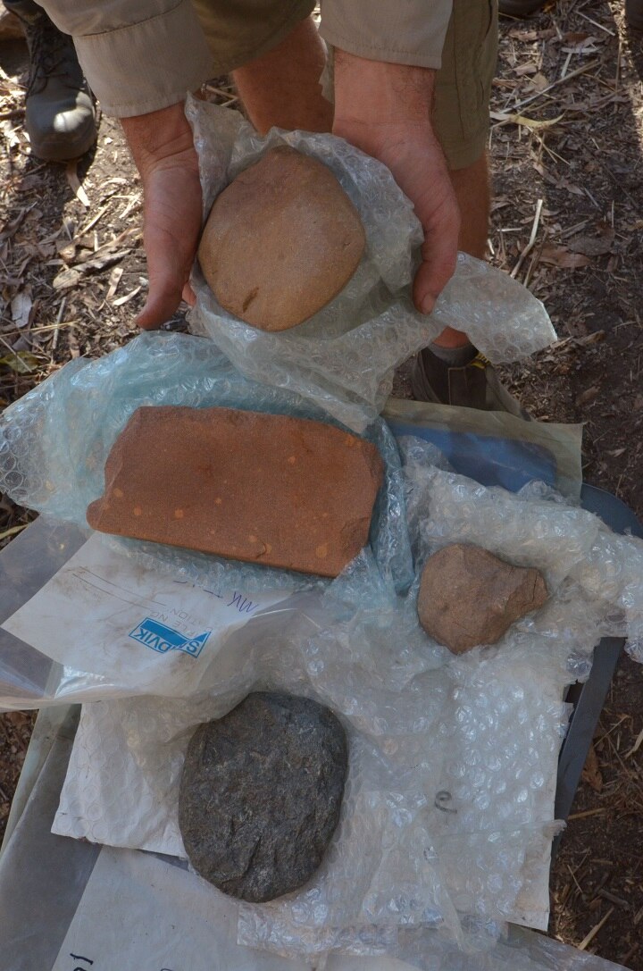 A close-up of three stones, one of which is held in a person's hands