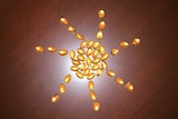 Golden-coloured capsules of vitamin D in the shape of a sun on a brown table