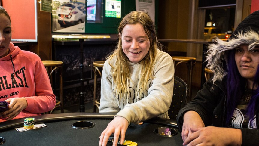 Poker player Sarah Wingrave sitting at the poker table flanked by two other female players.
