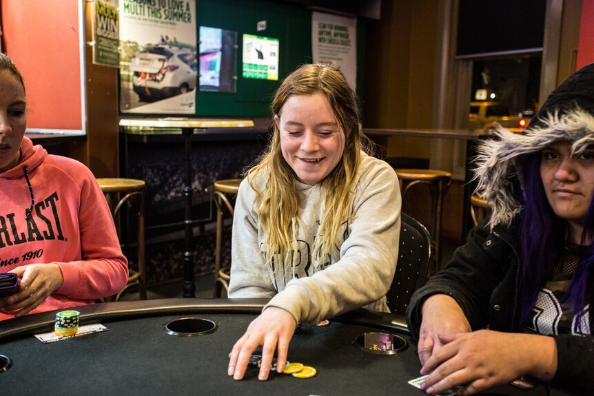 Poker player Sarah Wingrave sitting at the poker table flanked by two other female players.