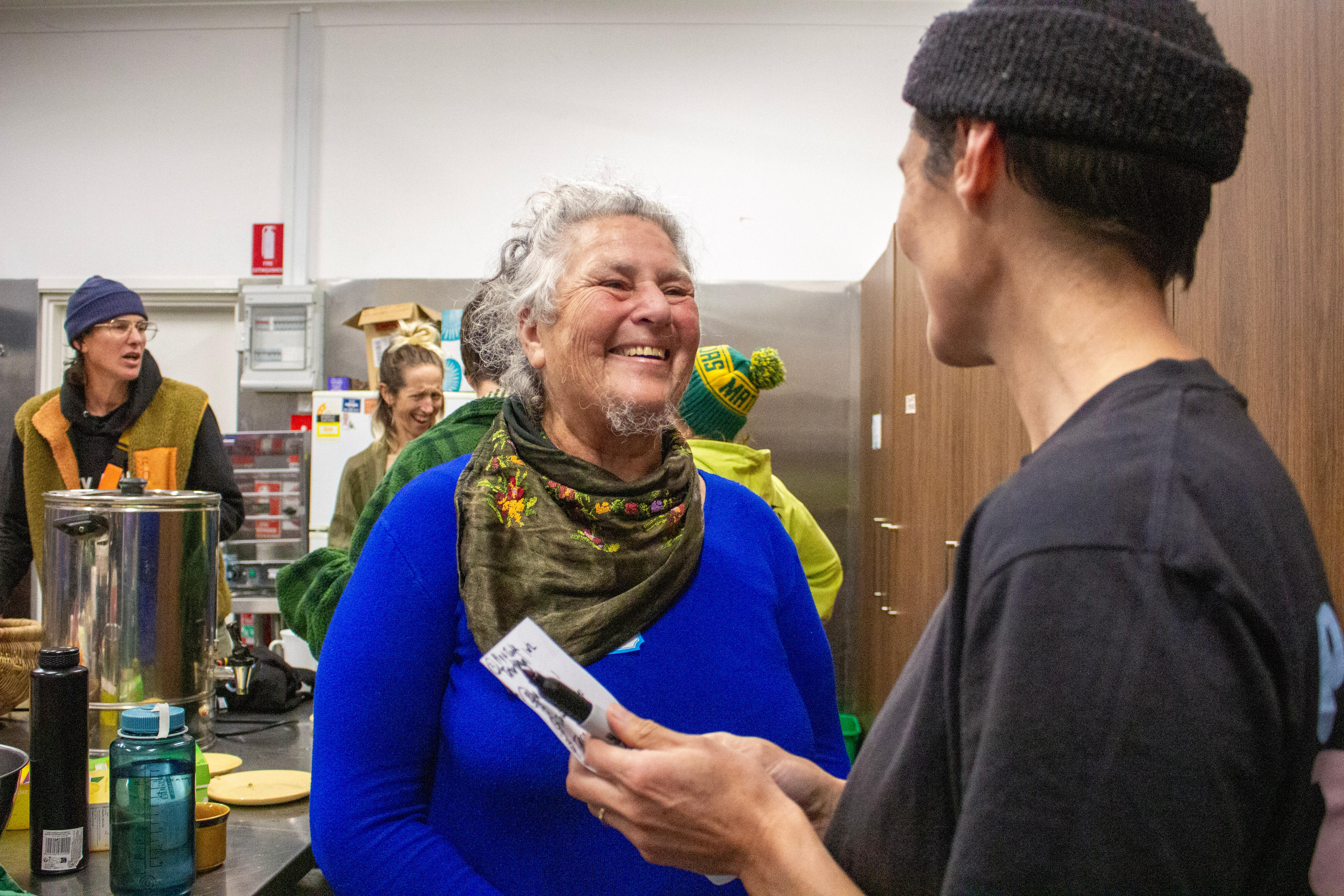 An older woman laughs while chatting to another person.
