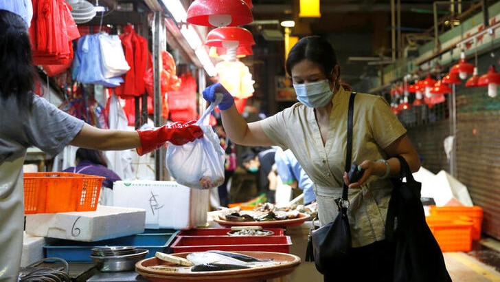 A woman wearing a surgical mask buys fish at a wet market following the coronavirus disease.