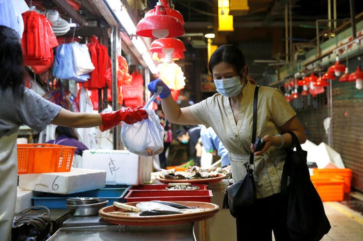 A woman wearing a surgical mask buys fish at a wet market following the coronavirus disease.